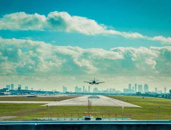 Airplane flying over runway against sky