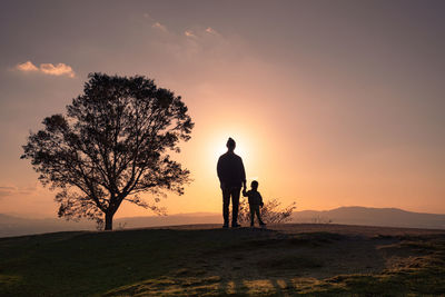 Silhouette man standing on field against sky during sunset