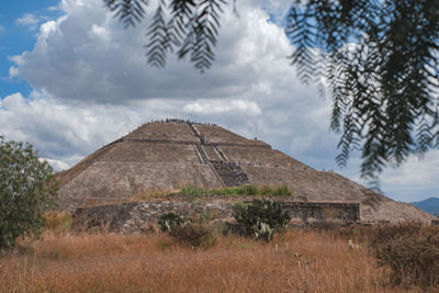 View of old mexican pyramid against cloudy sky