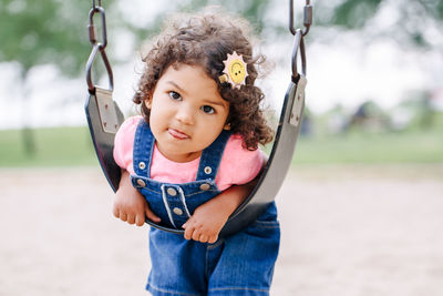Full length portrait of cute girl swinging at park