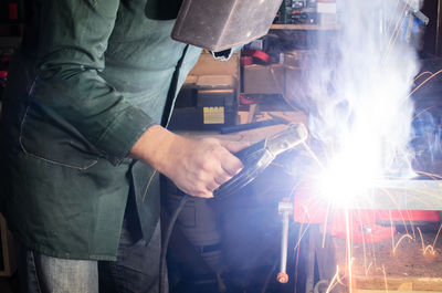 Midsection of man welding metal at workshop