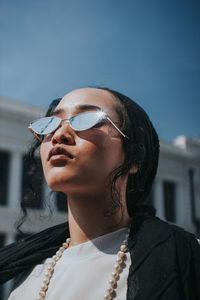 Close-up of young woman wearing sunglasses against blue sky