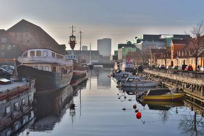 Boats moored at harbor by buildings in city