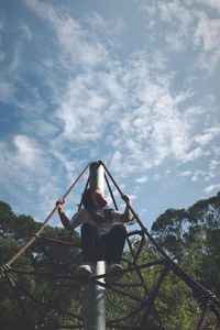 Low angle view of young woman standing by plants against sky