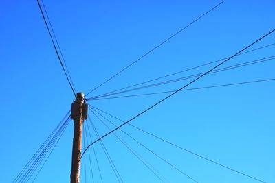 Low angle view of electricity pylon against blue sky