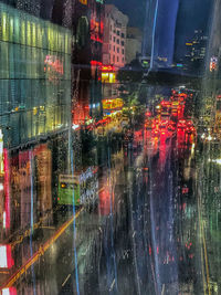 Illuminated city street seen through window at night