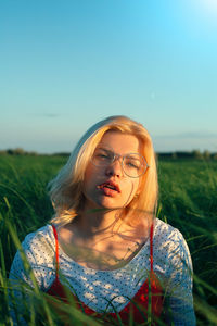 Portrait of woman wearing sunglasses on field against sky