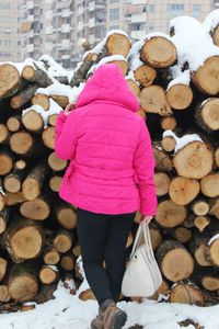 Rear view of woman standing by logs