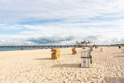 Hooded chairs on beach against sky