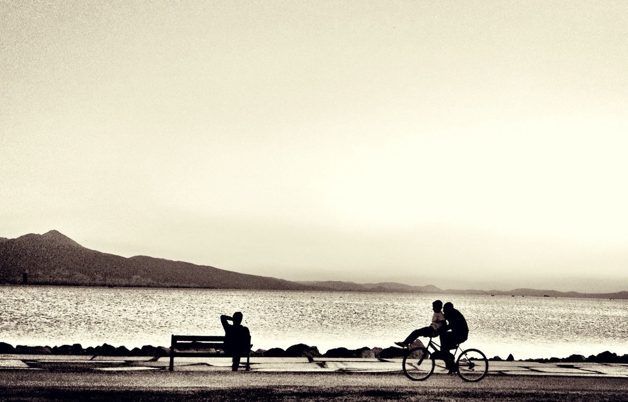 bicycle, transportation, mode of transport, water, men, lifestyles, land vehicle, leisure activity, riding, togetherness, full length, cycling, copy space, sitting, river, clear sky, sea