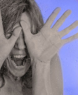 Close-up of woman gesturing seen through wet glass