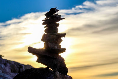 Close-up of stone stack on rock against sky during sunset