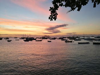 Silhouette boats moored in sea against sky during sunset