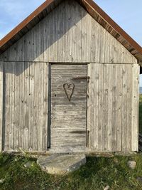 Closed wooden door on field against sky