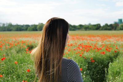 Rear view of woman standing on field against sky