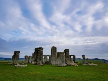 Stone henge on field against cloudy sky