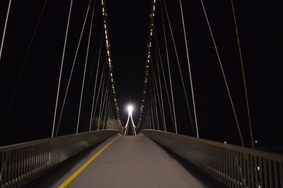Illuminated footbridge against clear sky at night