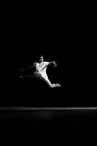 Full length of man dancing against black background