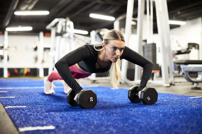 A woman doing push ups on the turf in the gym.