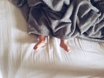 Low section of baby with blanket lying on bed