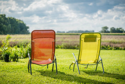 Empty chair on field against sky