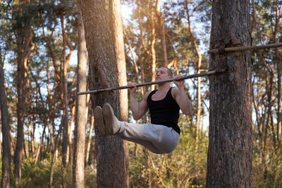 Man sitting on tree trunk in forest