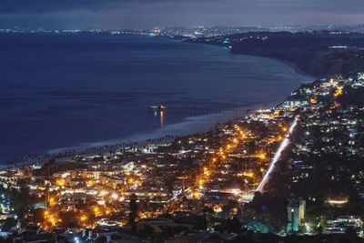 High angle view of illuminated town by sea at night