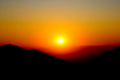 Scenic view of silhouette mountains against romantic sky at sunset