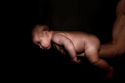 Midsection of shirtless man against black background