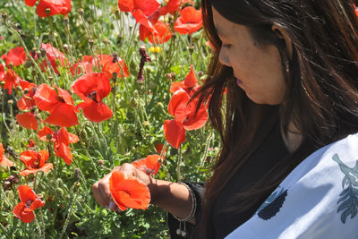 Portrait of woman with red flowers in field