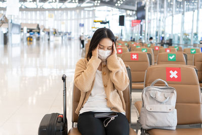Woman wearing mask sitting at airport lounge