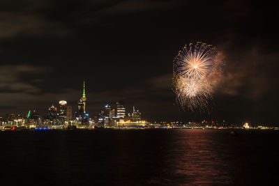 Firework display at night against cityscape