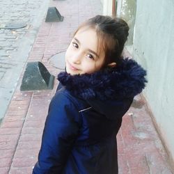 Portrait of girl standing against wall