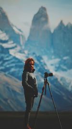 Low angle view of woman photographing on mountain