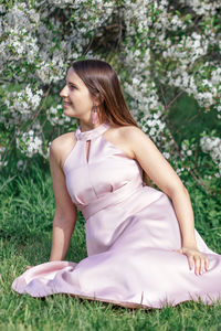 Side view of young woman sitting on grass