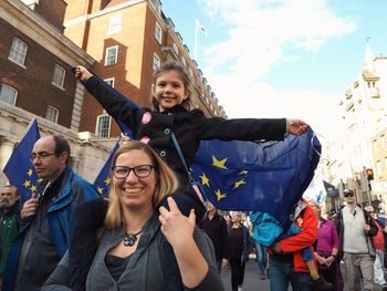 Portrait of smiling young woman with arms raised in city