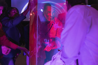 Happy businessman analyzing glass display by female colleagues in convention center