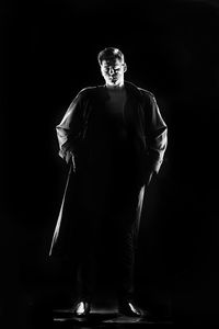 Portrait of man standing against black background