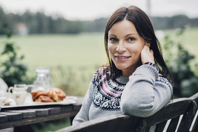 Portrait of smiling woman sitting at breakfast table in organic farm