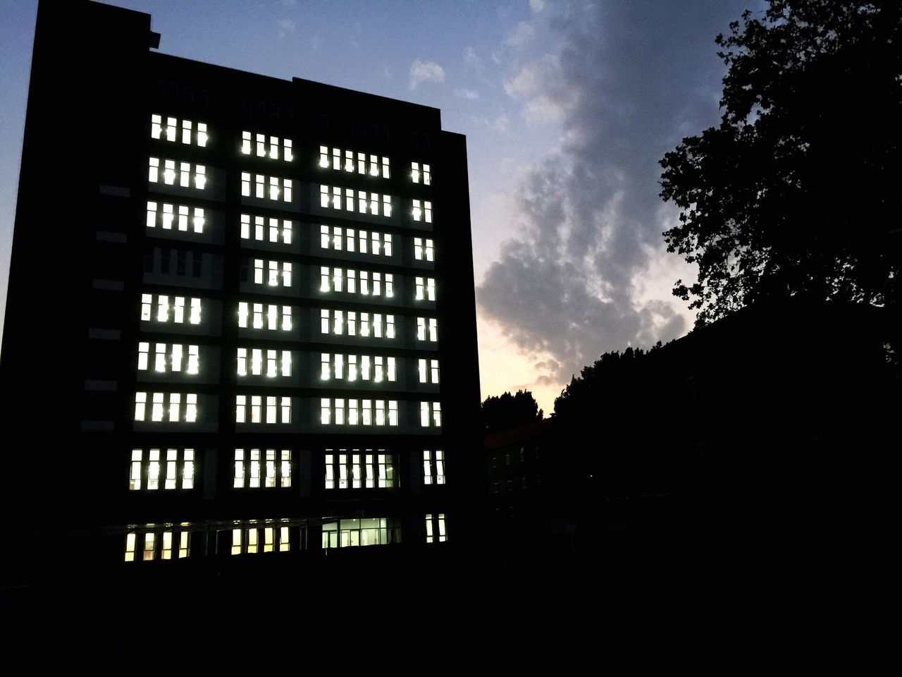 architecture, built structure, building exterior, sky, low angle view, cloud - sky, silhouette, building, tree, city, cloud, window, dusk, residential building, outdoors, no people, cloudy, dark, residential structure, sunset