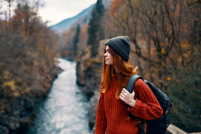 Woman looking away while standing on tree during winter