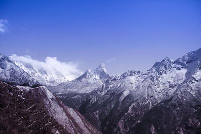 Scenic view of snowcapped mountains against blue sky