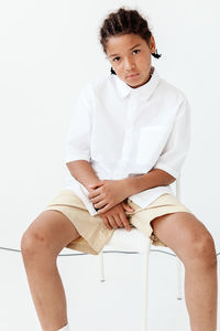 Young woman sitting against white background