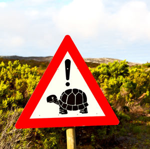 Close-up of road sign against sky