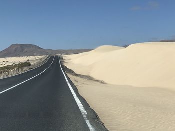 Road amidst desert against clear sky