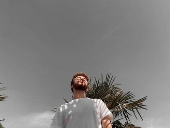 Low angle view of young man standing against sky