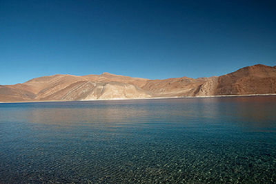 Scenic view of lake and mountains against clear blue sky