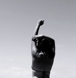 Rear view of a woman with arms raised against sky
