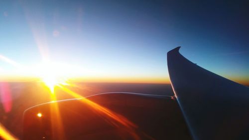 Close-up of airplane wing against sky during sunset