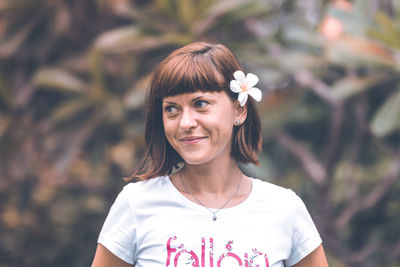 Portrait of young woman standing against plants